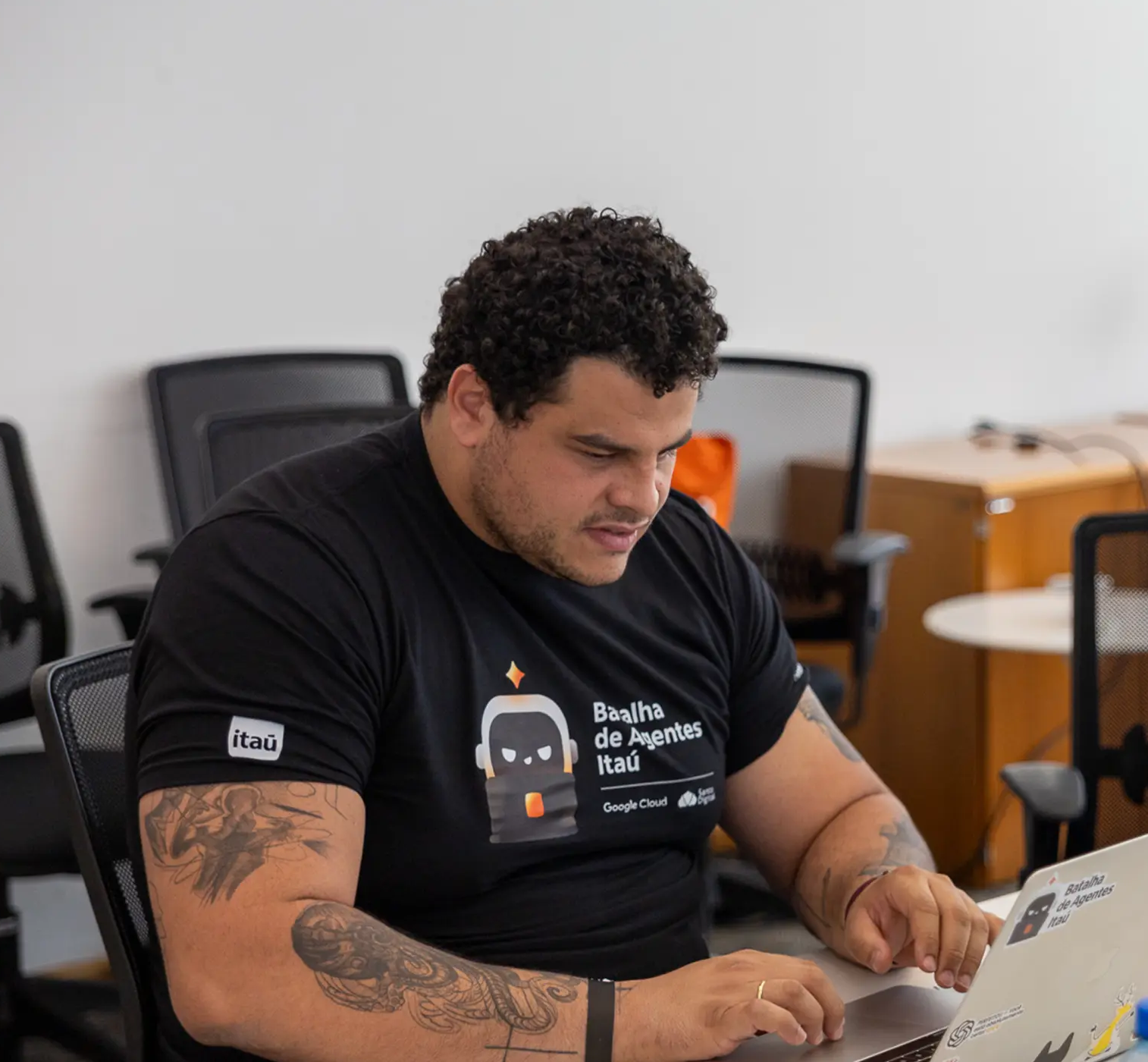 Danilo Marcello digitando no laptop durante a Batalha de Agentes do Itaú